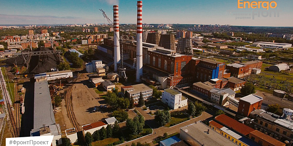 Aerial photograph of a thermal power plant with red and white chimneys, cooling towers and a coal warehouse in the city