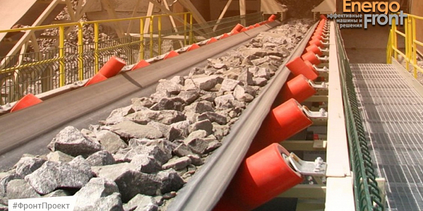 Conveyor belt with crushed stone on orange rollers on the platform