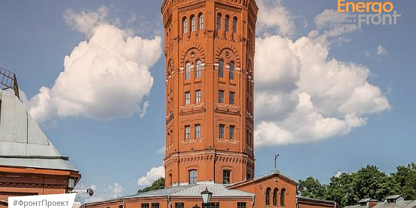 Historic red brick water tower against blue sky