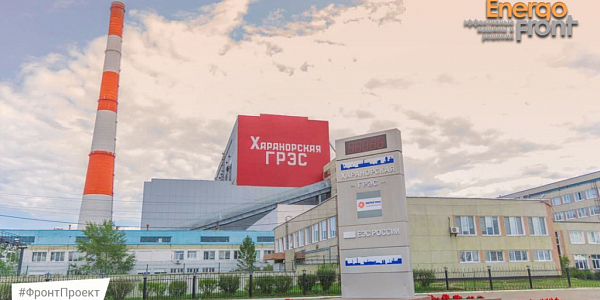 Facade of Kharanorskaya State District Power Plant with red inscription, pipe and Inter RAO stele