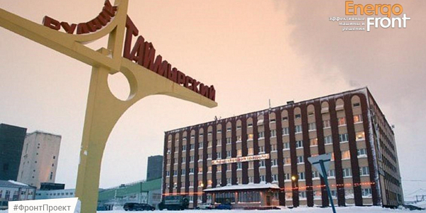 Winter view of the Taimyrsky mine: yellow sign and brick building under a pink sky