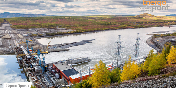 Hydroelectric dam on a wide river among the autumn tundra with cranes