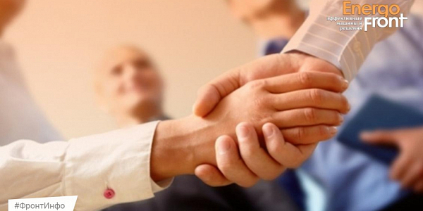 Close-up of a business handshake in an office with blurred colleagues in the background