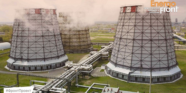 Three tall cooling towers and a network of insulated pipelines on a green area