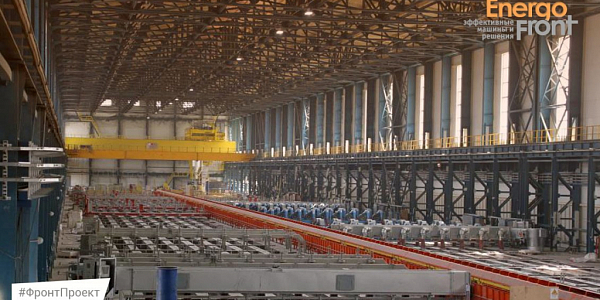 Long production hall with yellow overhead crane and rows of equipment