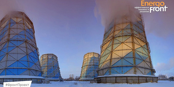 Four hyperboloid cooling towers in winter, steam rising from the right