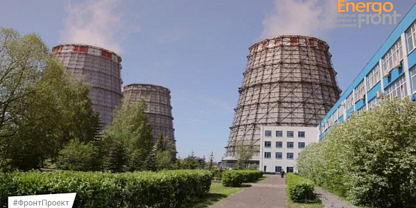 Three lattice cooling towers and a blue building shell on a green area