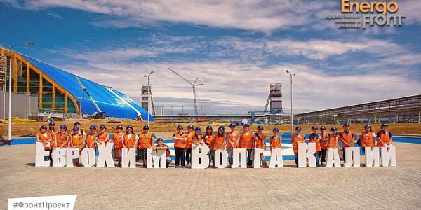 A group in orange vests near the three-dimensional letters Eurochem-Volgakaliy on the site