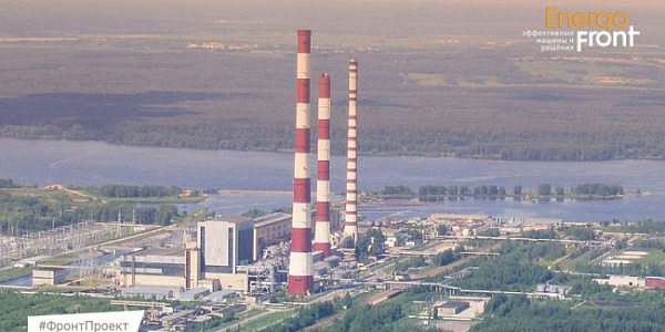 Aerial photo of a thermal plant with three red and white chimneys by the river