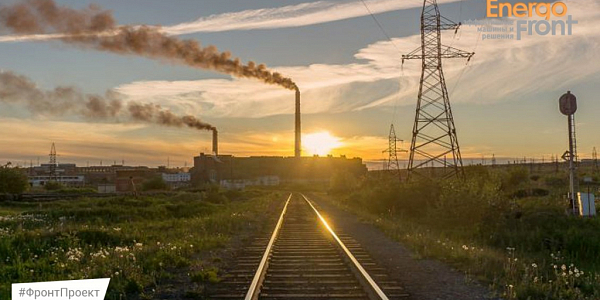Railway track to a factory at sunset with smoking chimneys