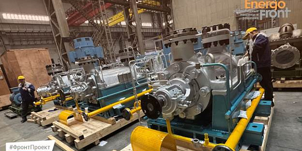 Large pumping units on pallets in the workshop, engineers checking the equipment