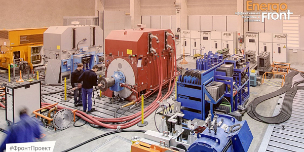 Technicians near a red electric motor on a test bench with control cabinets