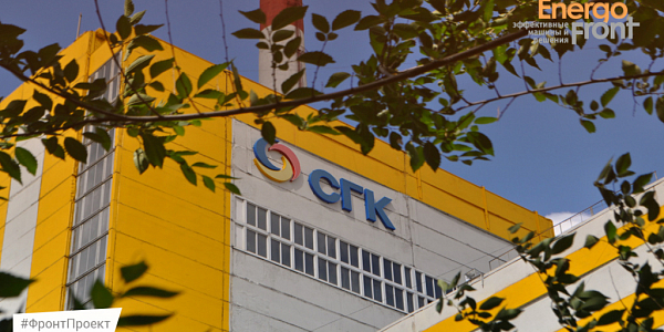 Yellow-white building of the SGK station with a pipe and branches in the foreground (Barnaul CHPP-3)