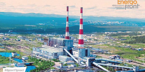 Aerial view of a thermal power plant with two striped chimneys and gray buildings among the hills