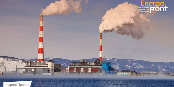 Thermal power plant near water in winter with two striped pipes and steam above the surface