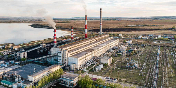 Aerial photograph of a thermal power plant with four striped pipes near a pond