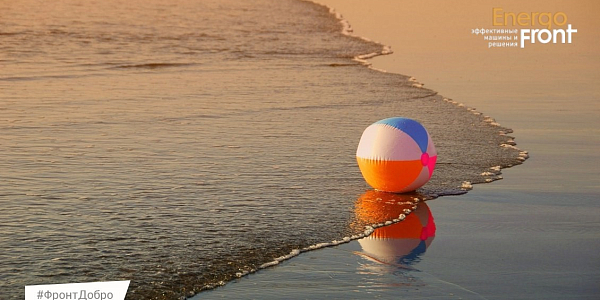 Multi-colored beach ball at the water's edge at sunset with the EnergoFront logo