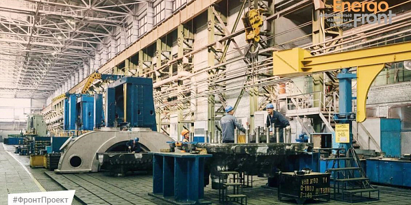 Workshop for assembling large metal components with workers in blue helmets