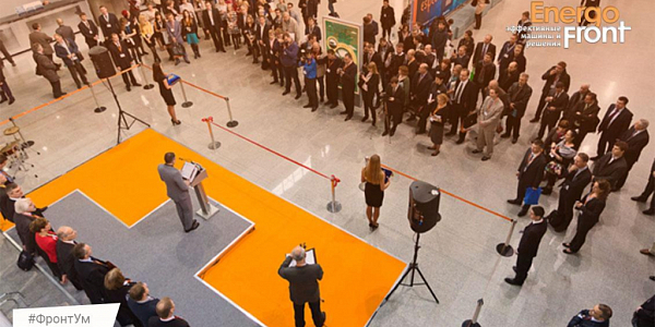 Speaker speaking on the orange stage in front of a business audience in the EnergoFront hall