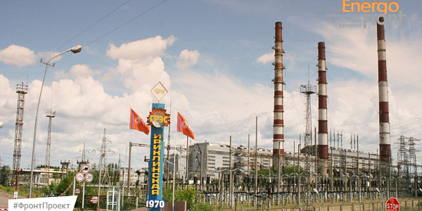 Stela of Iriklinskaya State District Power Plant 1970 against the background of striped pipes and a substation