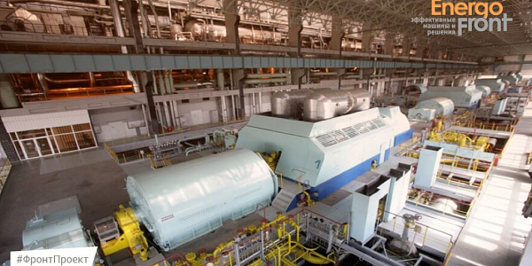 Spacious turbine room with a row of large turquoise turbine units and pipelines