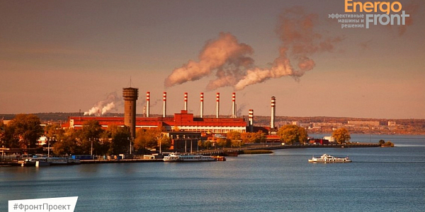 Industrial complex with red and white pipes on the river bank at sunset