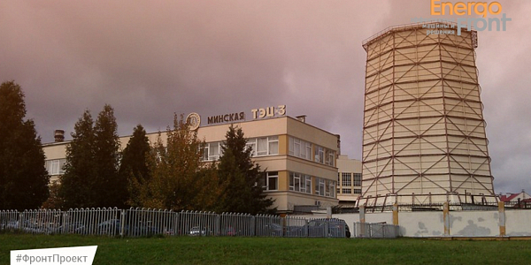 The building of Minsk CHPP-3 with a cooling tower behind a fence and trees