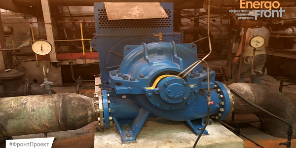 Blue horizontal centrifugal pump with flanged pipelines and pressure gauges in the workshop