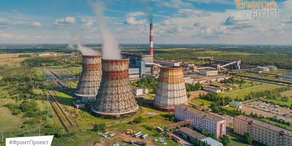 Three cooling towers of a thermal power plant with steam and a striped chimney among the fields