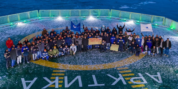 Group photo of the team on the helipad of the icebreaker Arktika with flags