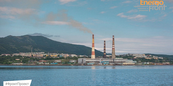 Coastal thermal power plant near the mountains with chimneys and water area in the foreground