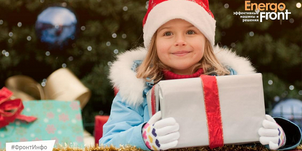 Smiling girl in a Santa hat with a gift near the New Year tree