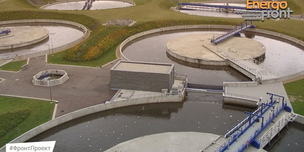 Round concrete wastewater treatment plant sumps with blue scraper bridges on top