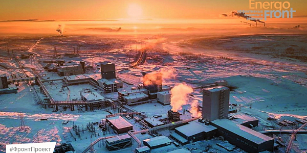 Aerial shot of a snow-covered industrial complex at sunset with steam coming out of the chimneys