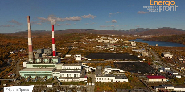 Aerial photo of a thermal power plant among autumn hills with a lake and coal warehouses